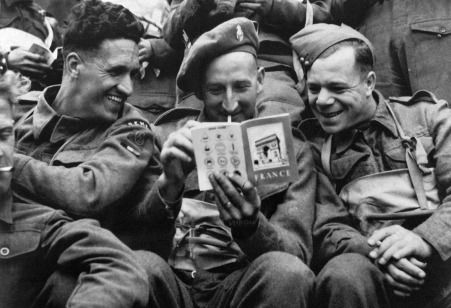 British troops take a light-hearted look at a brochure on France issued by their unit shortly before the invasion. (AFP)