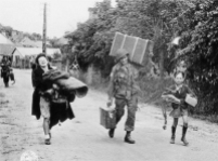 Private First Class Clayton C. Hayes of Fox Company, 505th Infantry Regiment helps Normandy residents, Madame Digeon and Jacques Birette, with their luggage along the Route de Chef-du-Pont on the outskirts of St-Mère-Église on June 8, 1944. Hayes would die in combat in Holland on September 20, 1944, during Operation Market Garden. (NARA 111-SC-190287)