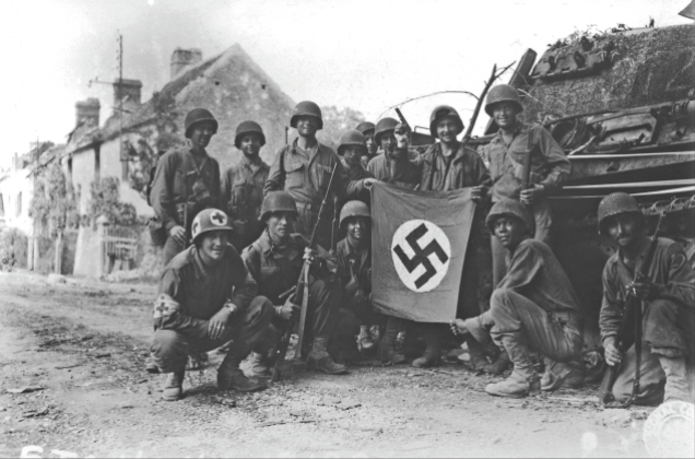 Americans of all creeds and colors come together to hold up a captured Nazi flag at Chambois, France, on 20 August 1944, a day before the collapse of German troops in the Falaise Pocket. Contrary to popular belief that the American segregation of the 1940s normalized racism to banal levels, an examination of narratives and memoires of the era shows that there actually existed a level of cordiality, if not mutual respect, among the various American peoples. That is not to say, however, that African Americans were not regarded as second-class citizens as a matter of official policy. (Corbis)